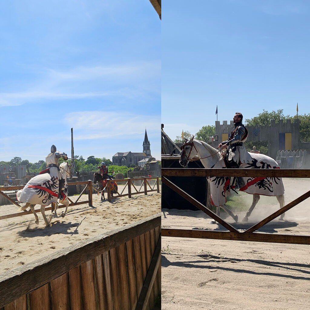 EIFA Two knights in medieval armor joust on horseback in an outdoor arena. Each knight wears a tunic with a red and black dragon emblem. The bilingual audience watches behind wooden barriers. A church steeple and a small castle are visible in the background, reminiscent of Londons historical charm.