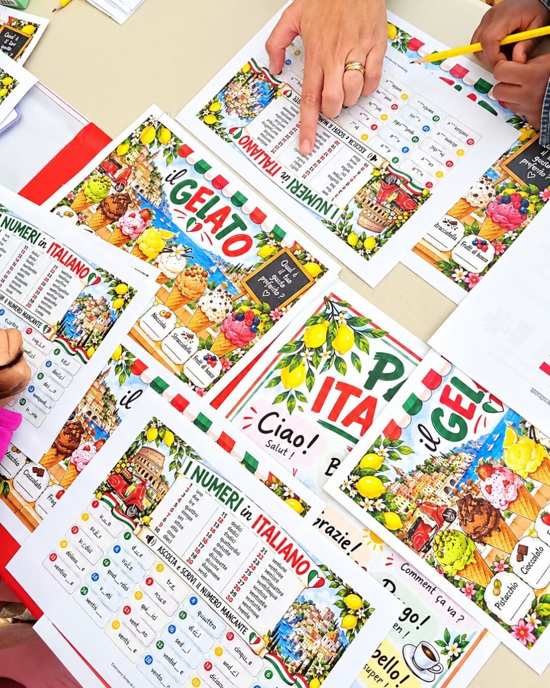 EIFA Des mains pointent vers des fiches d'exercices d'italien comportant des illustrations de glaces, de monuments italiens et des listes de vocabulaire numérotées.