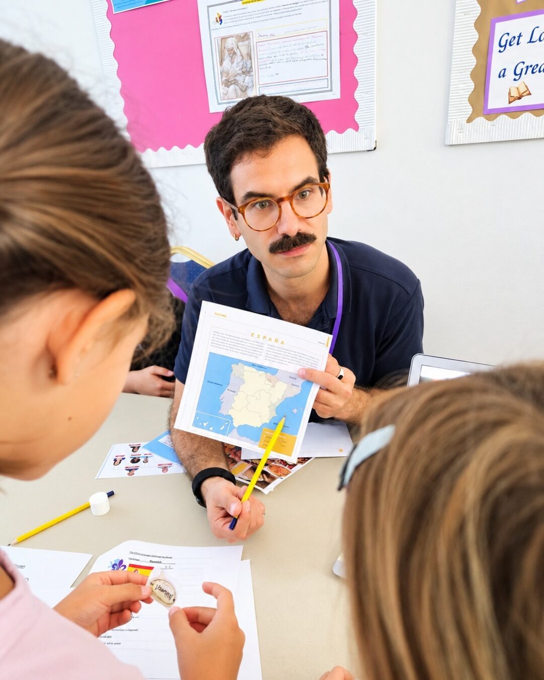 EIFA Pendant un cours, un enseignant montre une carte de l'Espagne à deux élèves assis à une table.