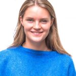 EIFA A young woman with straight, light brown hair and blue eyes is smiling. She is wearing a bright blue sweater and is posed against a plain white background.