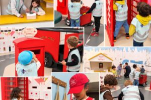 EIFA Des enfants vêtus de gilets réfléchissants jouent dans une maquette de bureau de poste comprenant une cabine téléphonique rouge, des chariots à courrier et un guichet, et découvrent ainsi des métiers mis à l’honneur lors de la Journée mondiale de l’alimentation.