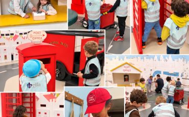 EIFA Des enfants vêtus de gilets réfléchissants jouent dans une maquette de bureau de poste comprenant une cabine téléphonique rouge, des chariots à courrier et un guichet, et découvrent ainsi des métiers mis à l’honneur lors de la Journée mondiale de l’alimentation.