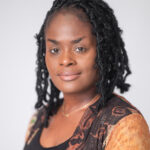 EIFA Portrait of a bilingual individual with shoulder-length braided hair, wearing a patterned jacket over a black top. They have a calm expression and are set against a plain light gray background, effortlessly bridging cultures in the heart of London.