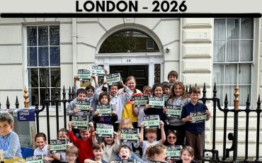 EIFA A group of children and adults pose outside a building, each holding a London 2026 marathon race bib. Above them, MARATHON and LONDON - 2026 are displayed in large, colorful letters for International Open Day.