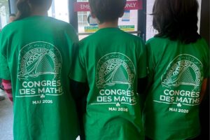 EIFA Three people stand indoors with their backs to the camera, wearing matching green shirts that read “CONGRÈS DES MATHS MAI 2026” with a mathematics-themed graphic above the text, celebrating International Open Day.