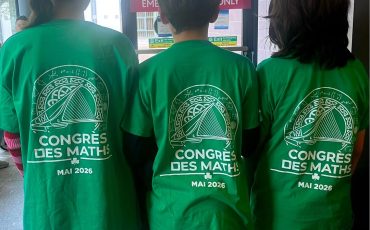 EIFA Three people stand indoors with their backs to the camera, wearing matching green shirts that read “CONGRÈS DES MATHS MAI 2026” with a mathematics-themed graphic above the text, celebrating International Open Day.