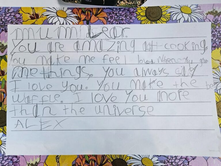EIFA A handwritten note on lined paper reads: Mummy Dear, You are amazing at cooking. You make me feel loved when you give me things. You always say I love you. You make the best waffles. I love you more than the universe. Alex.