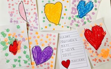 EIFA Seven handmade cards are displayed, each featuring colorful hearts and decorative dots or paint splatters. One card has a handwritten message: Happy Mothers Day! I love you signed by Nathan, with a small red heart drawing.