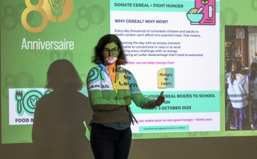 EIFA Une femme se tient devant une présentation projetée sur le don de céréales pour lutter contre la faim. La diapositive comporte du texte, des graphiques et des photos relatifs à un événement organisé par la banque alimentaire et à la célébration d’un huitième anniversaire. EIFA Une femme se tient devant une présentation projetée sur le don de céréales pour lutter contre la faim. La diapositive comporte du texte, des graphiques et des photos relatifs à un événement organisé par la banque alimentaire et à la célébration d'un huitième anniversaire.