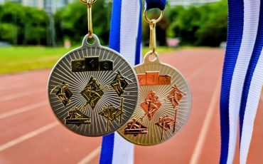 EIFA Deux médailles, l'une d'or et l'autre d'argent, sont suspendues à des rubans bleus et blancs devant une piste de course en plein air. Marquant la première et la deuxième place, elles célèbrent la réussite - parfaites pour honorer les gagnants lors de la Journée mondiale de l'alimentation.