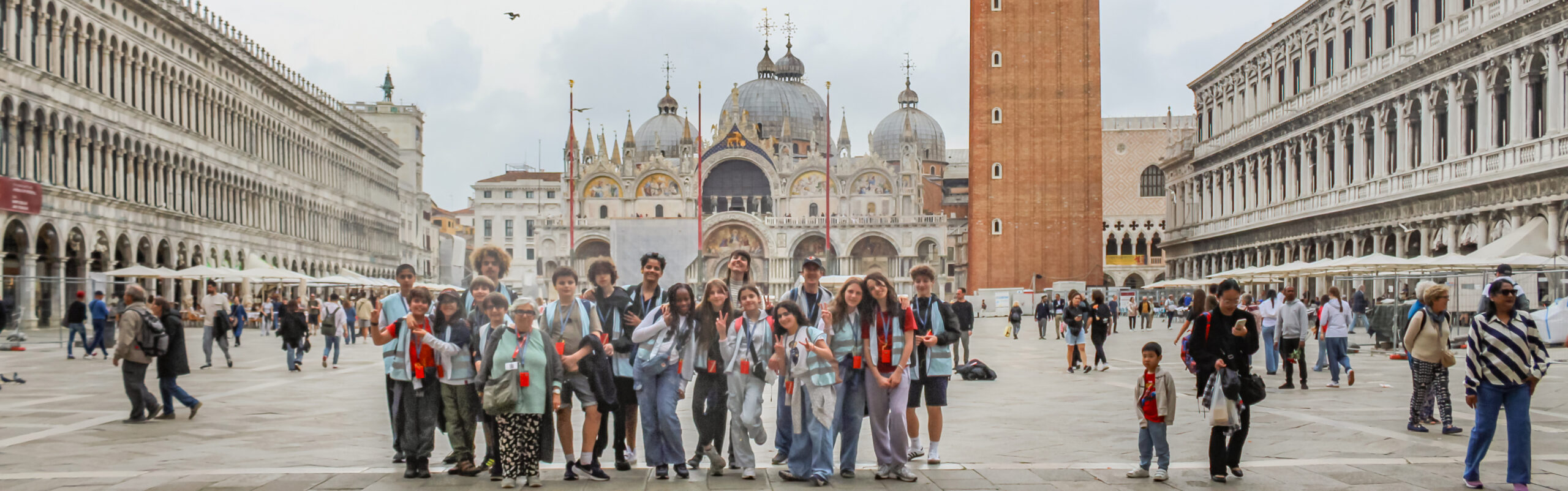 EIFA A group of people pose for a photo in St. Mark’s Square in Venice, Italy, with St. Mark’s Basilica and the Campanile behind them—just as Year 3 and Year 4 visited the Isle of Wight, they’re enjoying a lively plaza filled with tourists and historic buildings.