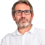 EIFA A man with short brown hair, a beard, and glasses, wearing a white collared shirt, stands against a plain white background with his arms crossed and a neutral expression, reflecting the professionalism of our dedicated and experienced team.
